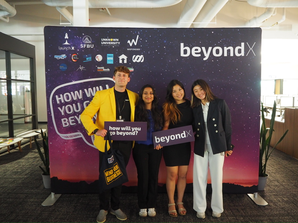 Attendees in front of the BeyondX how will you go beyond backdrop